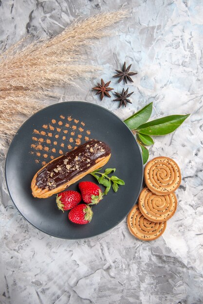 Вид сверху вкусные шоколадные эклеры с печеньем на легком бисквитном десертном пироге