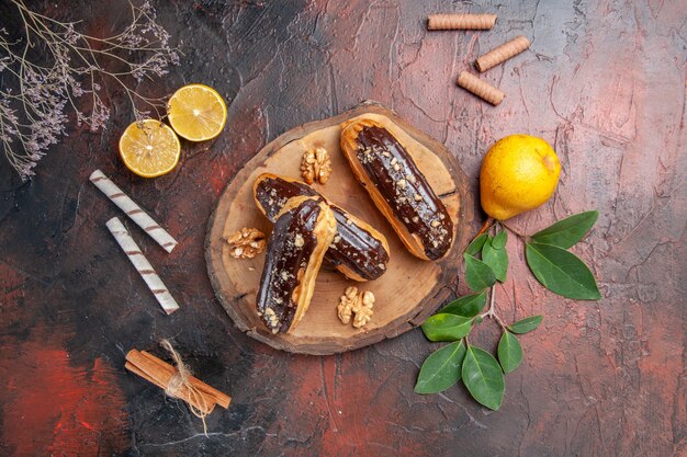 Top view yummy choco eclairs with fruits on the dark table cake dessert sweet