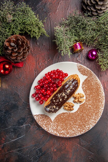 Top view yummy choco eclairs with red berries on dark table cake pie dessert sweet