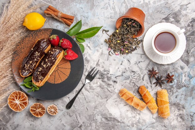 Top view yummy choco eclairs with tea on white cookie cake dessert biscuit