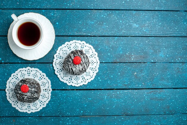 Вид сверху вкусные шоколадные шарики с чашкой чая на синем деревенском столе чайный торт печенье печенье сладкое