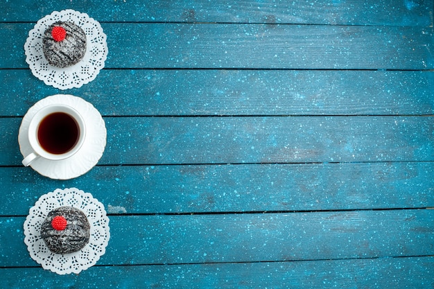 Vista dall'alto gustose palline di cioccolato con una tazza di tè sul dolce del biscotto della torta del tè della scrivania rustica blu