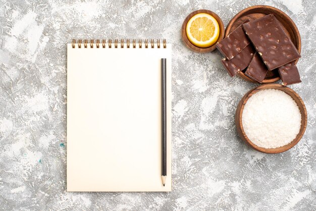 Top view of yummy chocolate bars with lemon slice on a white surface