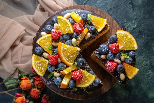 Top view yummy chocolate cake with fruits on dark 