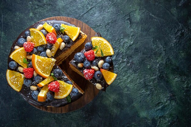 Top view yummy chocolate cake with fruits on dark 