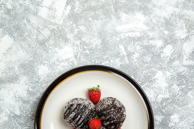 Foto gratuita vista dall'alto deliziose torte al cioccolato con fragole rosse fresche sulla scrivania bianca