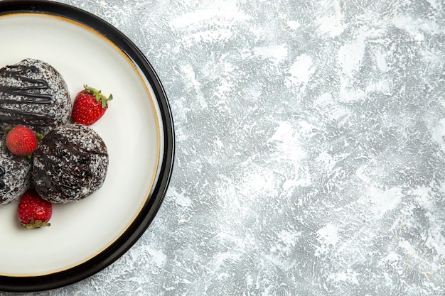 Vista dall'alto deliziose torte al cioccolato con fragole fresche su superficie bianca