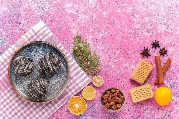 Top view yummy chocolate cakes with waffles and cinnamon on pink