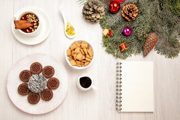 白い机の上に小さなココアケーキとお茶とトップビューおいしいチョコレートクッキー