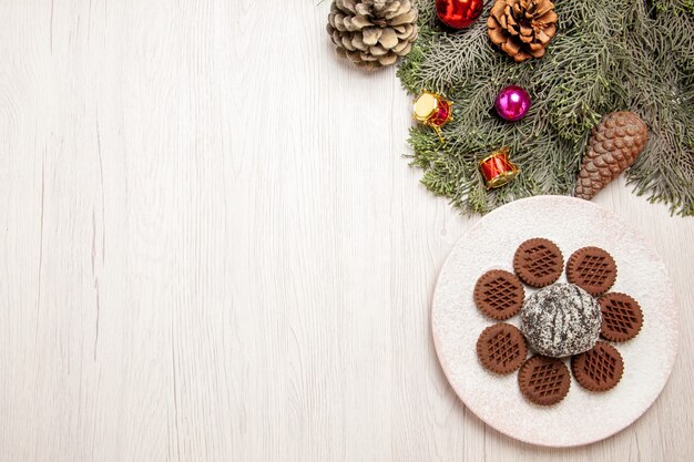 Top view yummy chocolate cookies with little cocoa cake on white