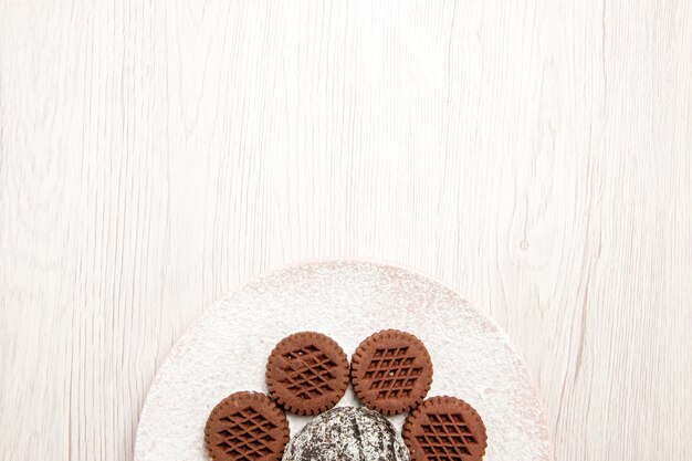 Top view yummy chocolate cookies with little cocoa cake on white