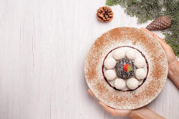 Foto gratuita vista dall'alto di deliziose caramelle al cocco con torta al cacao su bianco