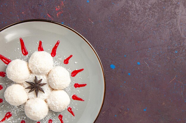 Top view of yummy coconut candies with red icings on black