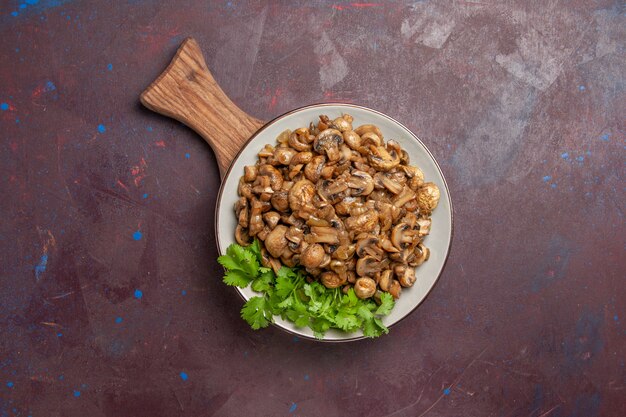 Top view yummy cooked mushrooms with greens on a dark