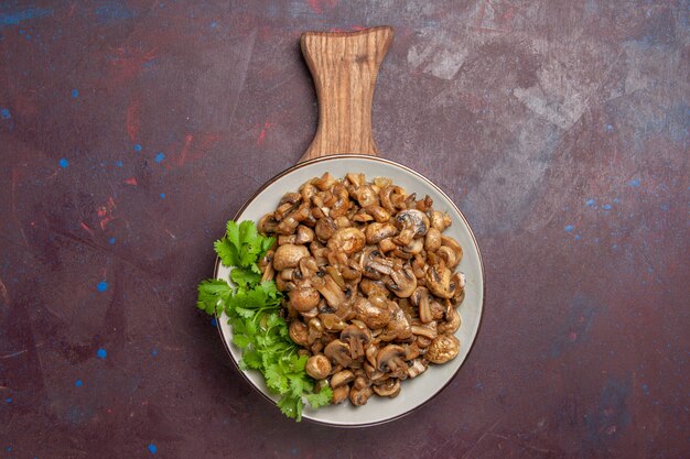 Top view yummy cooked mushrooms with greens on dark