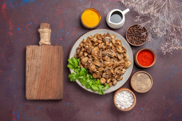 Top view yummy cooked mushrooms with greens and seasonings on dark