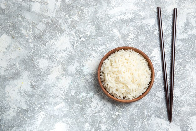 Вид сверху вкусный приготовленный рис внутри коричневой тарелки на белом