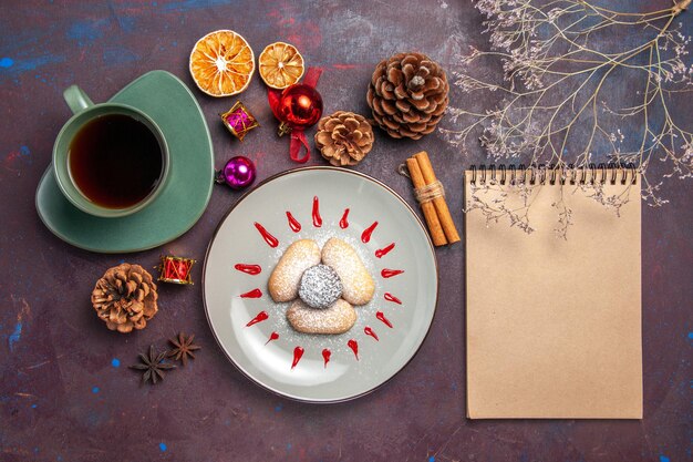 Top view of yummy cookies with cup of tea on black