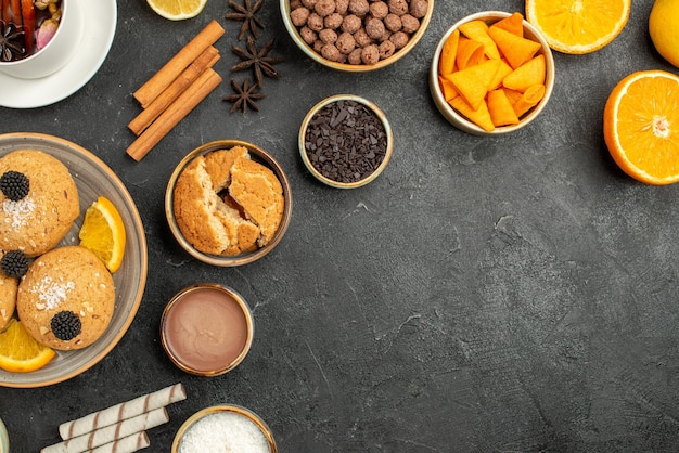 Top view yummy cookies with cup of tea and orange slices on a dark surface cake pie sugar dessert biscuit tea