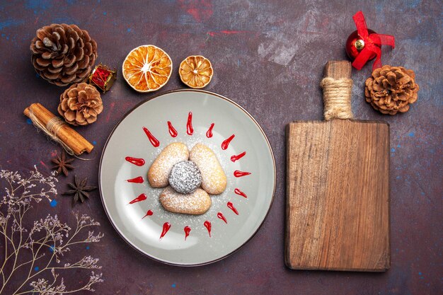 Top view of yummy cookies with red icings inside plate on black