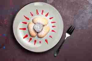 Free photo top view of yummy cookies with sugar powder and red icing inside plate on black