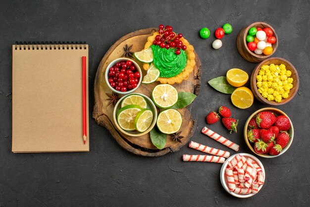 Top view yummy creamy cake with candies and fruits on dark floor sweet cookie biscuit