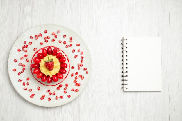 Top view yummy creamy cake with dogwoods on light white desk