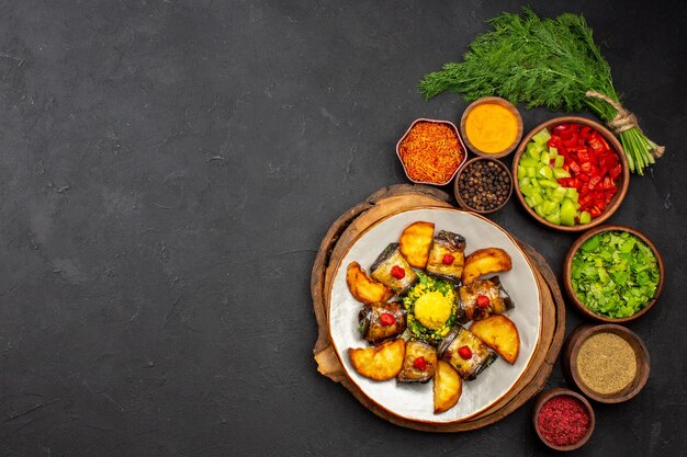 上面図おいしい茄子は、ジャガイモとさまざまな調味料を使った調理済みの料理を暗い表面の料理に巻きます食事ディナーフード