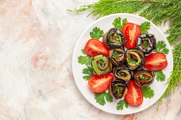 Top view yummy eggplant rolls with greens and tomatoes