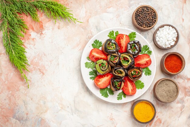 Top view yummy eggplant rolls with greens and tomatoes