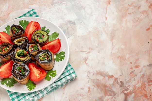 Top view yummy eggplant rolls with tomatoes and greens