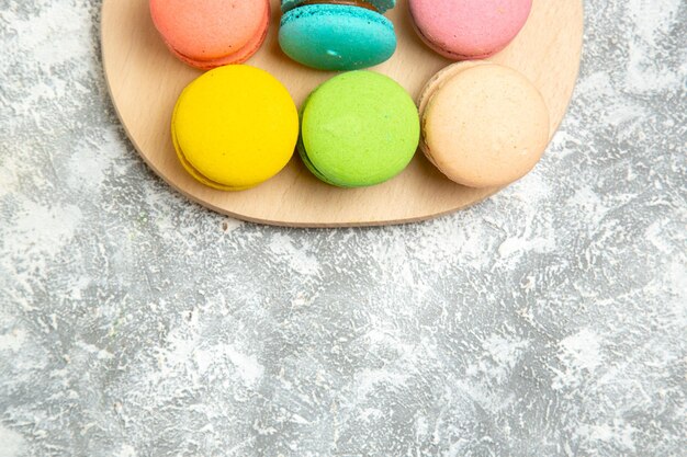 Top view yummy french macarons colorful cakes on the white surface