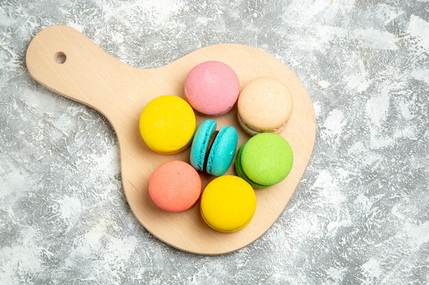 Top view yummy french macarons colorful cakes on white surface