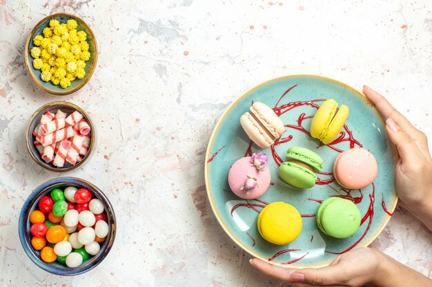 Top view yummy french macarons with candies on a white cake biscuit sweet