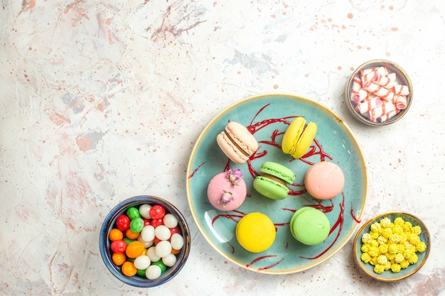 Top view yummy french macarons with candies on white sweet cake biscuit