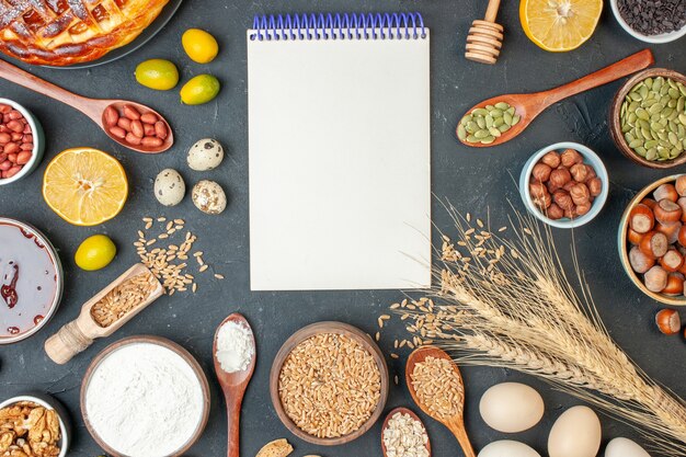 Foto gratuita vista dall'alto torta di frutta gustosa con blocco note e noci su torta di foto di noci di pasta di colore scuro torta di biscotti all'uvetta dessert