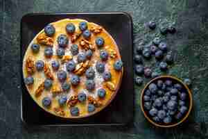 Free photo top view yummy honey cake with blueberries and walnuts inside plate dark surface