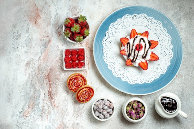 Top view yummy little cake with cookies and fruits on white