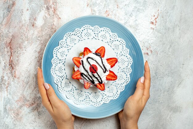 Top view yummy little cake with cream and strawberries on white