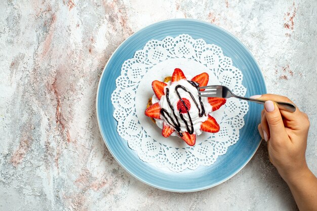 Top view yummy little cake with cream and strawberries on white