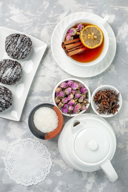 Top view yummy little cakes chocolate cakes with cup of tea on light-white background