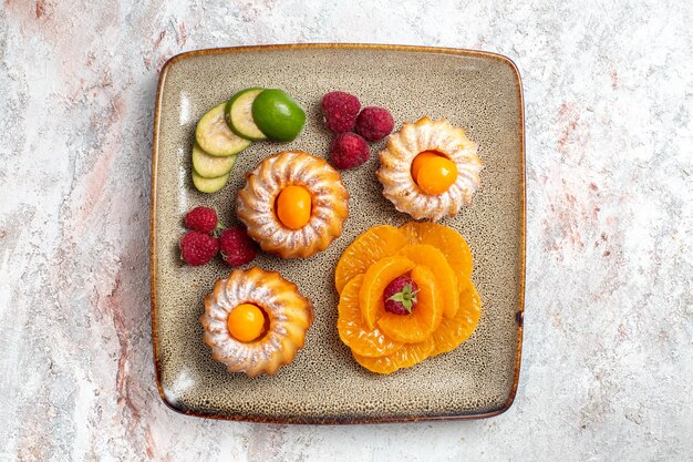 白地にスライスしたフルーツとおいしい小さなケーキの上面図