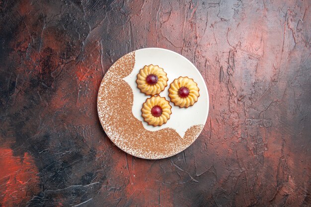 Top view yummy little cookies inside plate on a dark table sweet biscuit cake