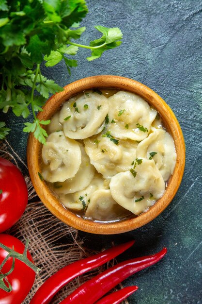 어두운 표면에 신선한 토마토와 채소가 들어간 맛있는 고기 만두