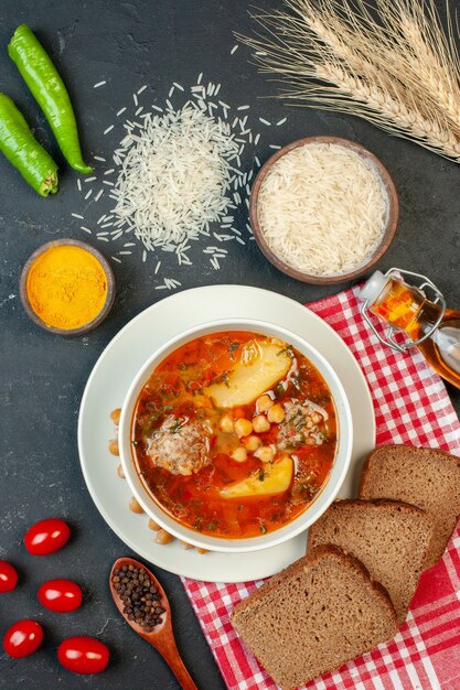 Бесплатное фото Вид сверху вкусный мясной суп с хлебом и помидорами на темном фоне