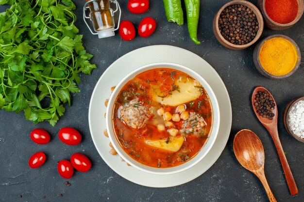 Top view yummy meat soup with greens and seasonings on dark background