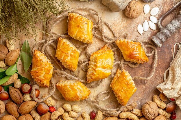 Top view of yummy nut pastries with fresh nuts on the brown desk