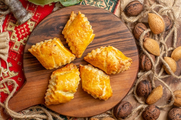 Top view of yummy nut pastries with fresh walnuts on a brown desk