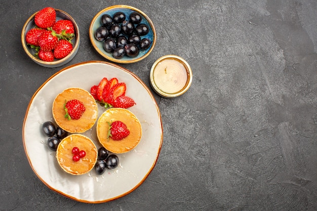 Top view yummy pancakes little formed with fruits on grey