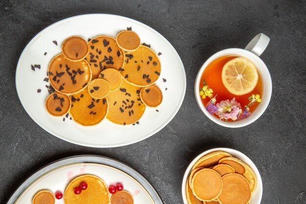 Top view yummy pancakes with cup of tea on the dark background